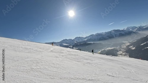 Family skiing. Father is skiing ahead and his children are skiing behind him. Beautiful ski resort with sunny weather in Bellwald, Switzerland. photo