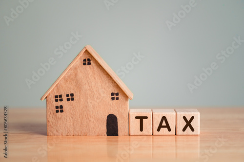 Property tax or house tax with wooden model on table top background. Business loan and real estate investment concept.