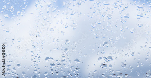 Raindrops on the glass, blue sky and clouds in the background