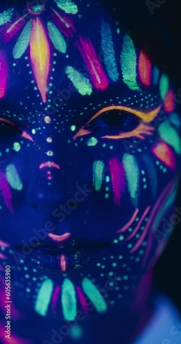Wallpaper Mural Vertical Screen: Beauty Footage in Close Up: Young Female Poses with Confidence, Neon Paint Accentuating Her Facial Features Against an Abstract Dark Studio Setting, Creating an Artistic Composition Torontodigital.ca