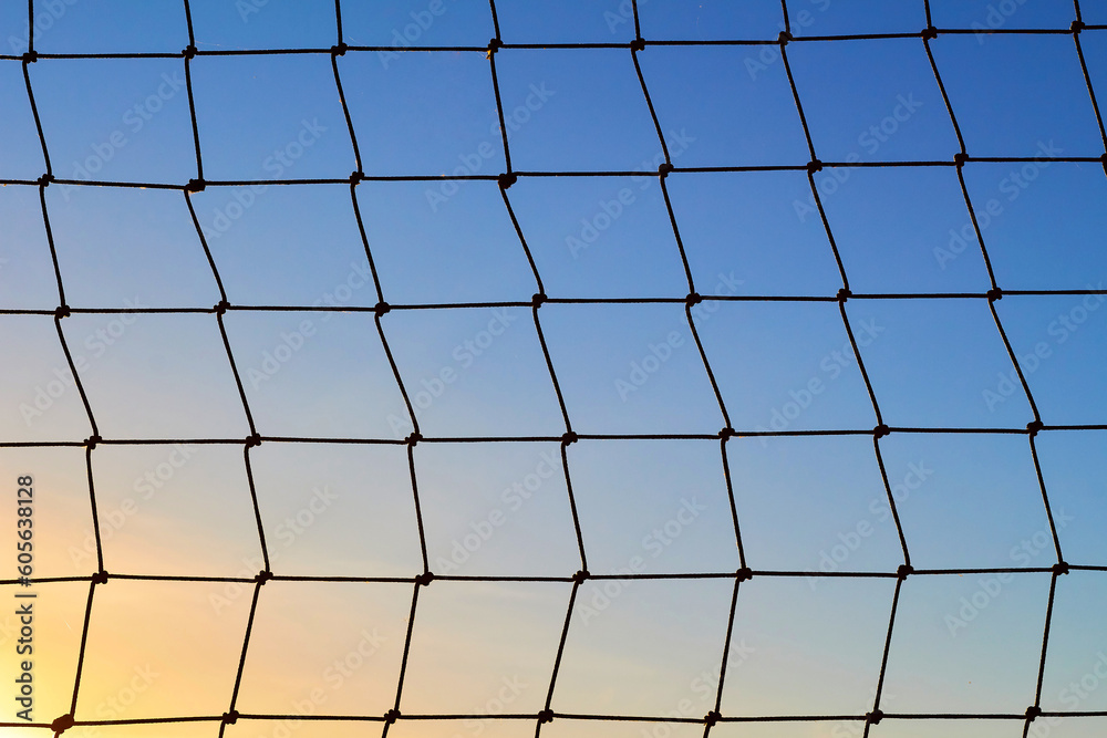Net to catch balls around a football field, on clear blue sunset sky background