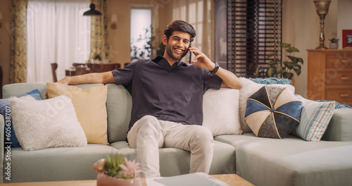 Charismatic Indian Man Engaged in Phone Call, Doing Remote Work and Social Life. Handsome Happy, Smiling Guy Helping Customers with Products, Talks to Family or Friends. Medium Shot 