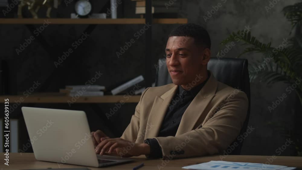 An African American businessman sits in his home office and communicates with his partners via video call. Smiling black man communicates via laptop webcam. An African American businessman sits in his home office and communicates with his partners via video call. Smiling black man communicates via laptop webcam.
