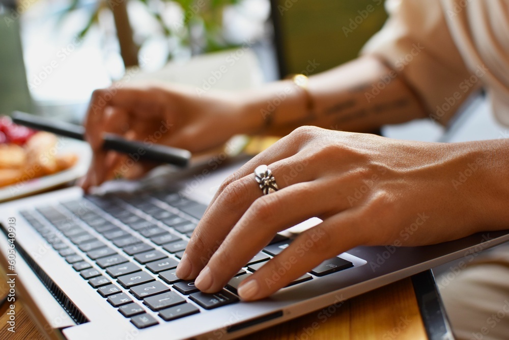 Selective focus of a female person working on a laptop in a cafe Selective focus of a female person working on a laptop in a cafe