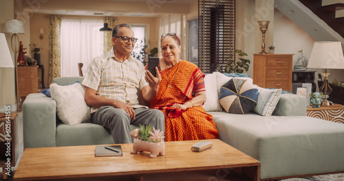 Amazing Elderly Indian Couple Using Smartphone for Video Call at Home. Beautiful Hindu Granparents Waving and Greeting Grandchildren, Talking with Relatives and Friends. Medium 