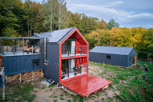 New modern house cottage with solar photovoltaic panel system on roof. Aerial view. Concept of alternative, renewable energy and home autonomy.