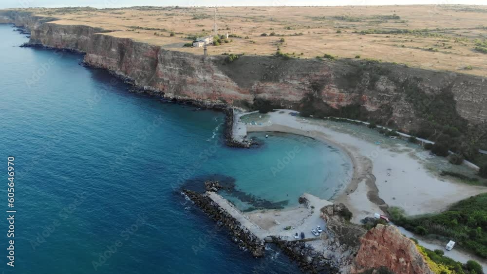 Aerial of a huge cliff and the calm blue sea with the horizon in the background during the sunset Aerial of a huge cliff and the calm blue sea with the horizon in the background during the sunset