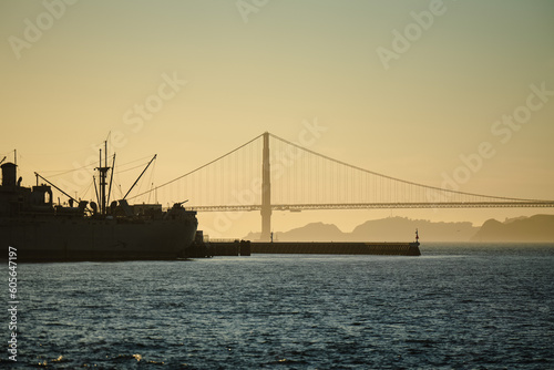Golden Gate Bridge at sunset and a silhouette of a ship on San Francisco Bay