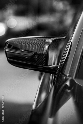 Vertical grayscale partial view of a car side-view mirror