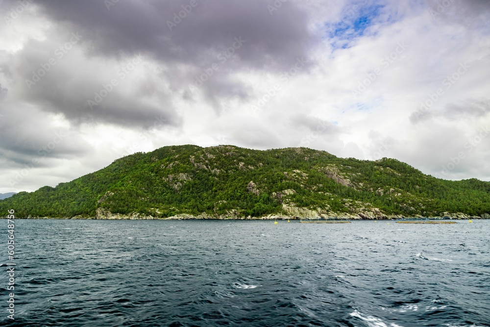 Beautiful landscape of a lake with calm waters surrounded by rocky mountains in cloudy weather