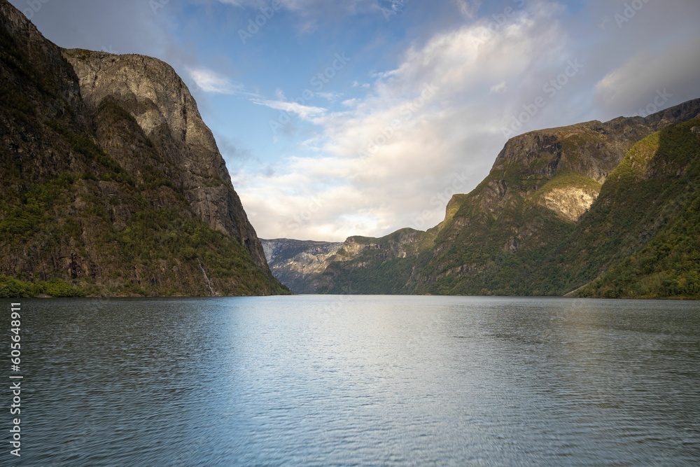 Scenic view of huge rocky mountains in cloudy sky background surrounded by the lake Scenic view of huge rocky mountains in cloudy sky background surrounded by the lake