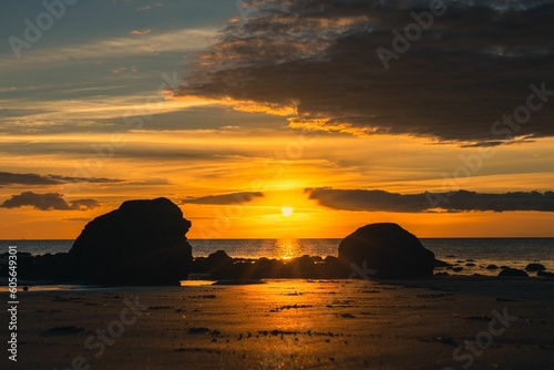 Beautiful orange sunset on a rocky shore with a cloudy sky in the background