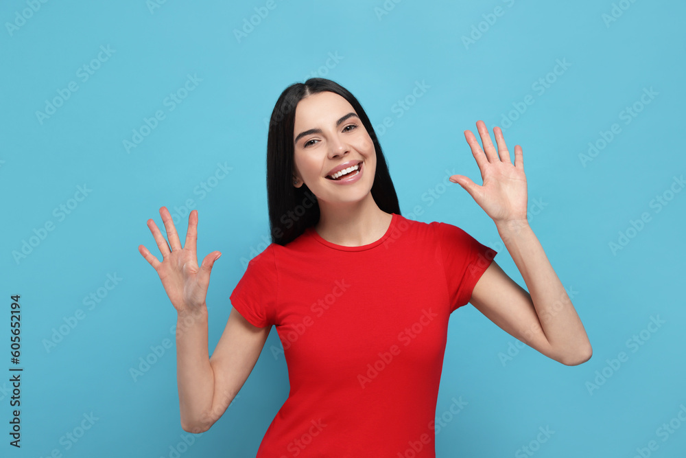 Happy woman giving high five with both hands on light blue background