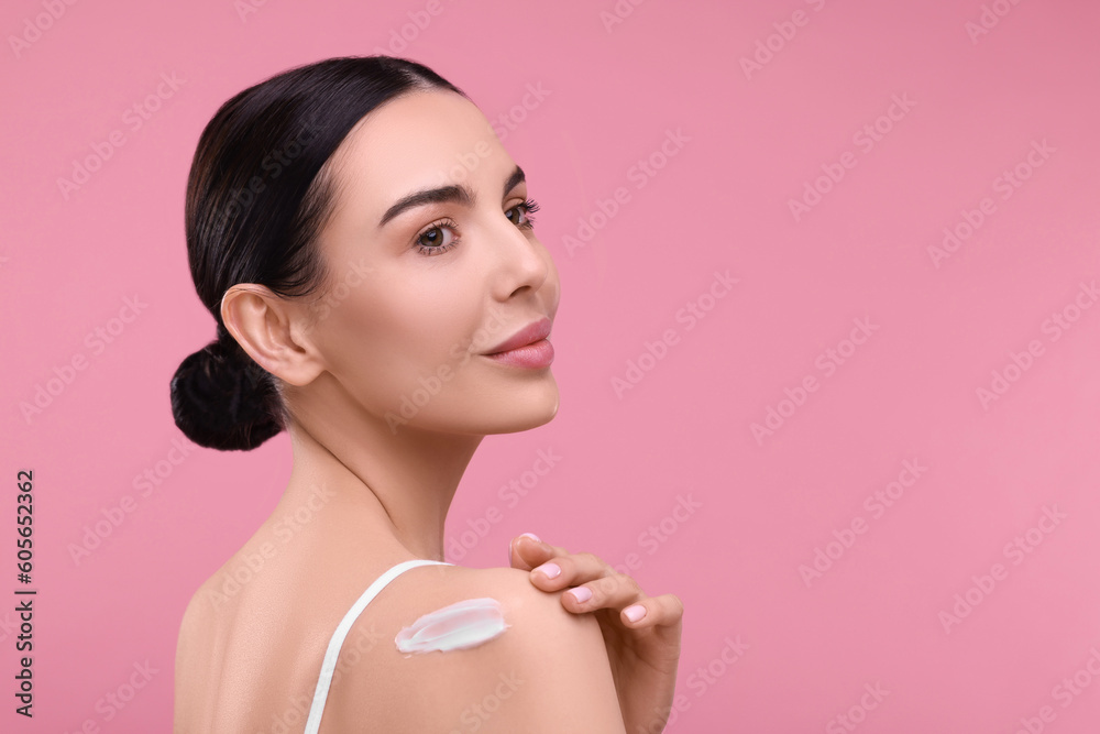 Beautiful woman with smear of body cream on her shoulder against pink background, space for text Beautiful woman with smear of body cream on her shoulder against pink background, space for text