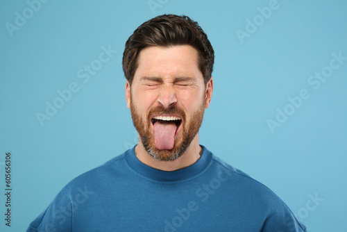 Man showing his tongue on light blue background