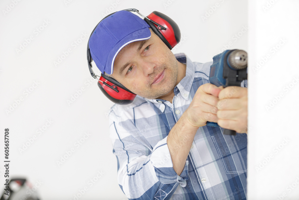 builder wearing protective workwear and holding electric drill