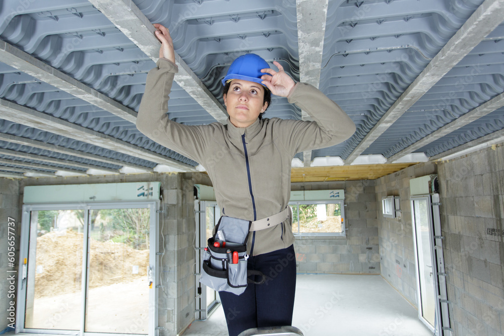 female construction worker examining the interior of a roof