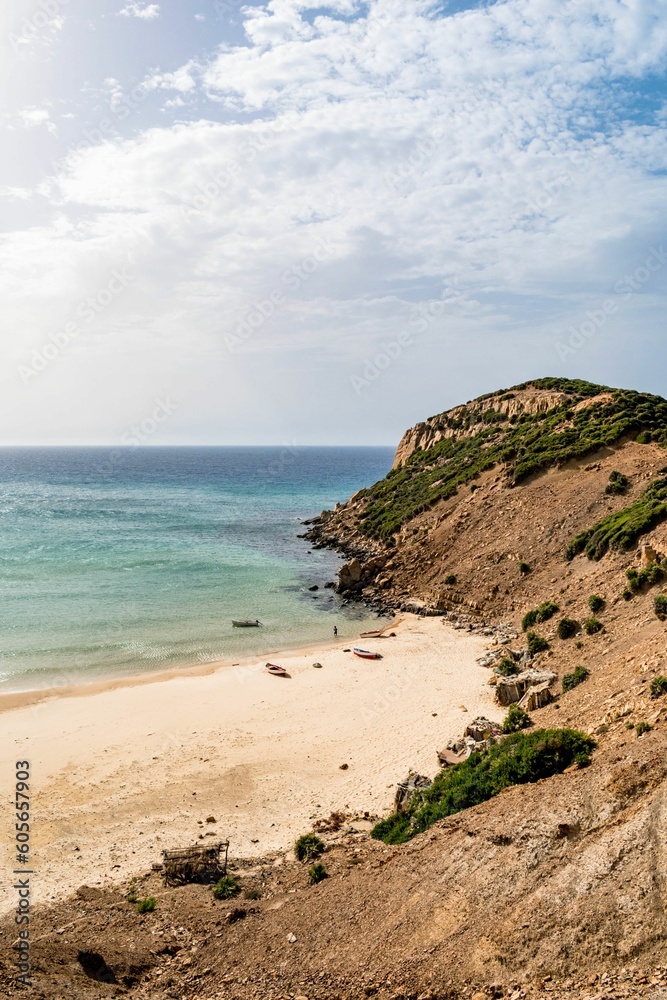 Vertical shot of a sunny rocky seashore on a summer day in Kef Abbed, Tunisia