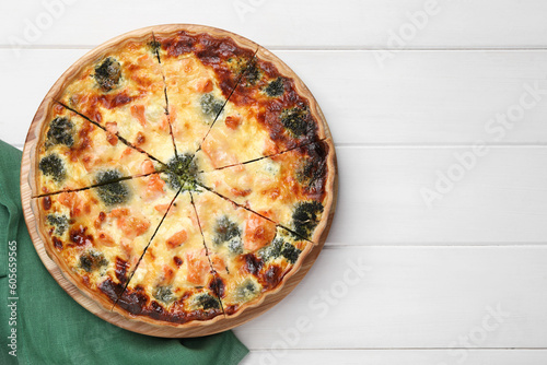 Delicious homemade quiche with salmon and broccoli on white wooden table, top view. Space for text
