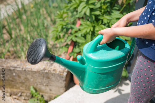 Happy little girl watering vegetable garden in spring © 24K-Production