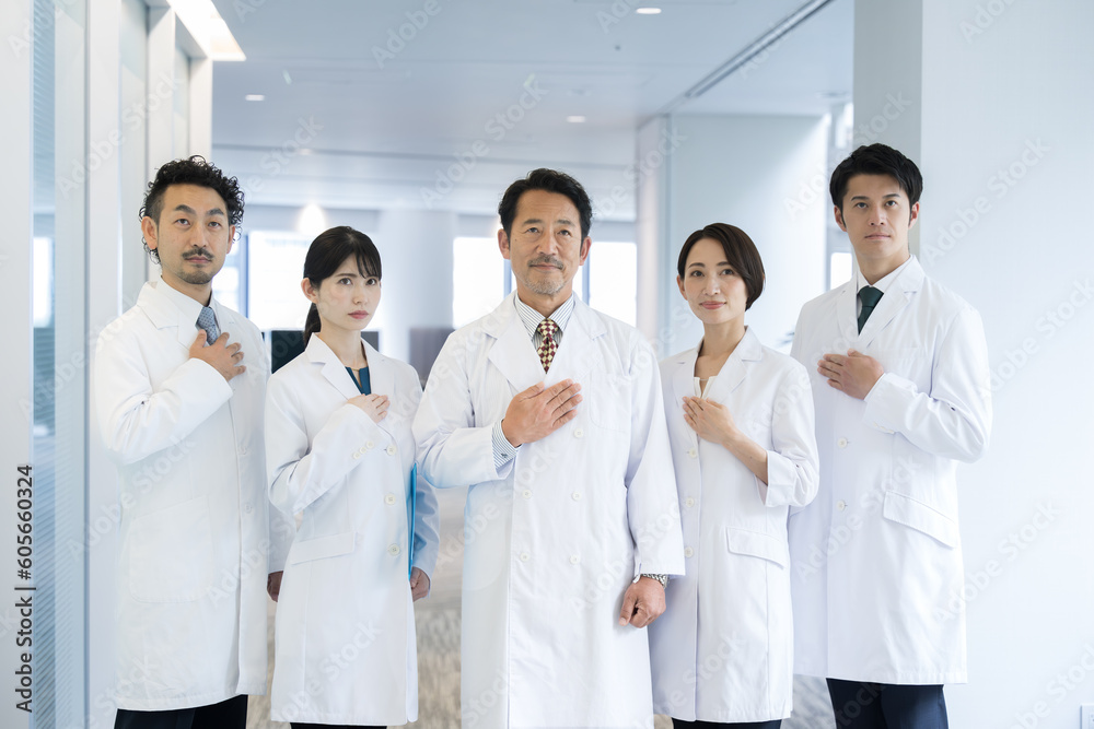 All together image of multiple doctors and researchers all looking at the camera, hands on chest All together image of multiple doctors and researchers all looking at the camera, hands on chest