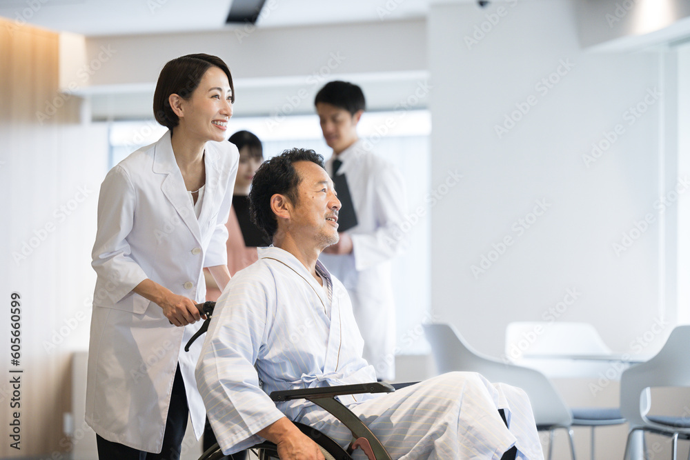 Fototapeta premium 大きな病院で介護や看護される車いすに乗った男性とドクターと看護師