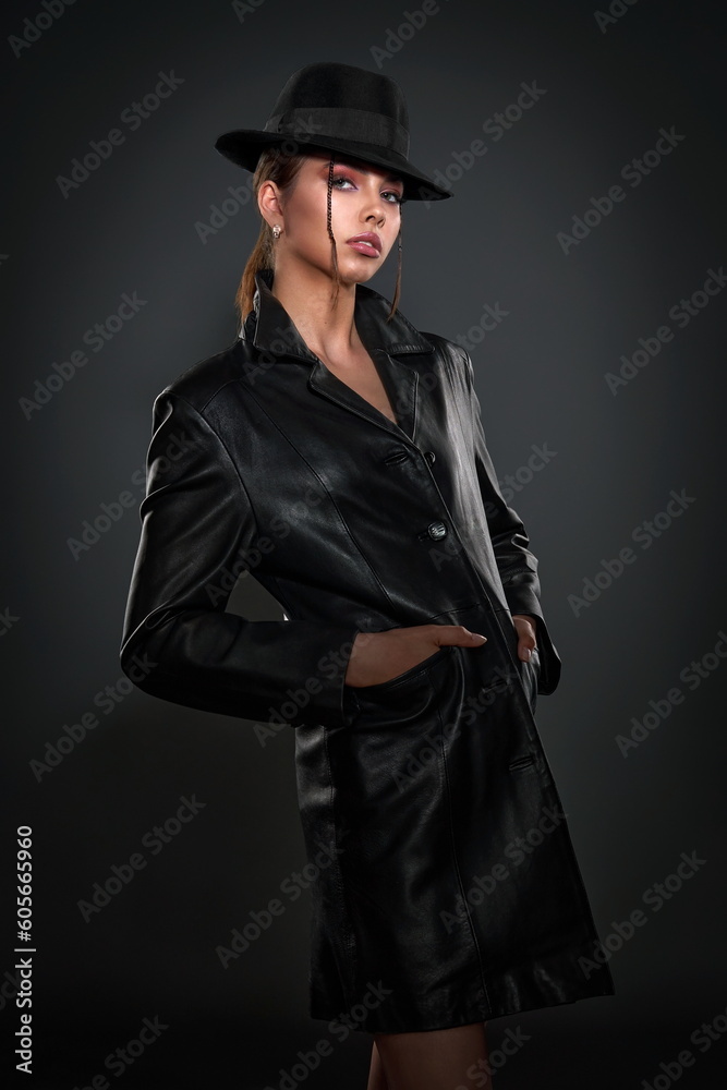 beautiful girl in a black leather coat and a black men's hat posing in the studio beautiful girl in a black leather coat and a black men's hat posing in the studio