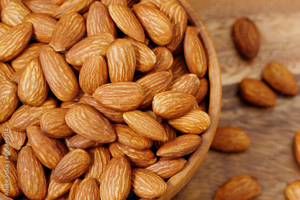 Fototapeta premium Organic almond nut raw peeled in bowl on wooden table, top view. Healthy snack or for vegetarians. copy space banner.