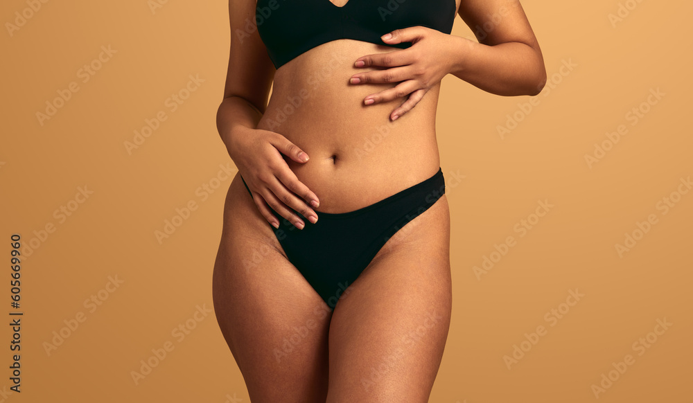 Crop unrecognizable woman with curvy body touching belly - obrazy, fototapety, plakaty 