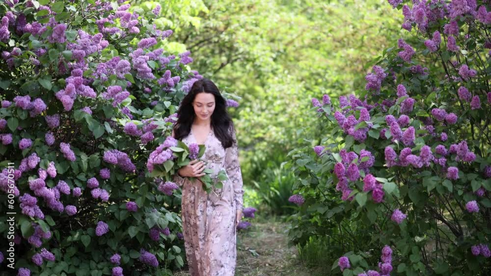 Young woman walks in garden with bouquet and enjoys by blooming lilac shrubs. Young woman walks in garden with bouquet and enjoys by blooming lilac shrubs.