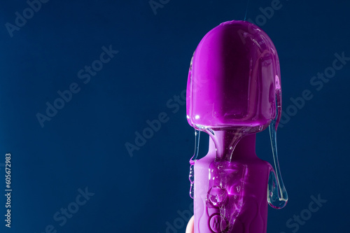Intimate lubricant pours on a purple vibrator on a blue background. Copy space.  photo