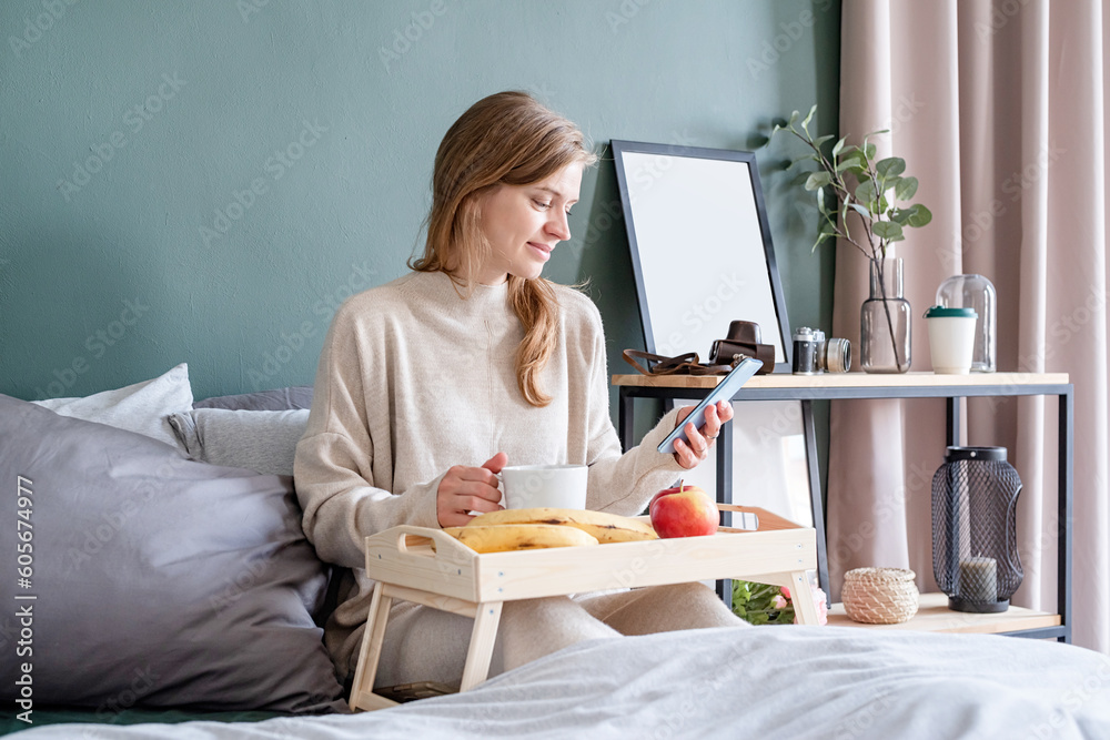 Woman sitting at bed at home drinking coffee