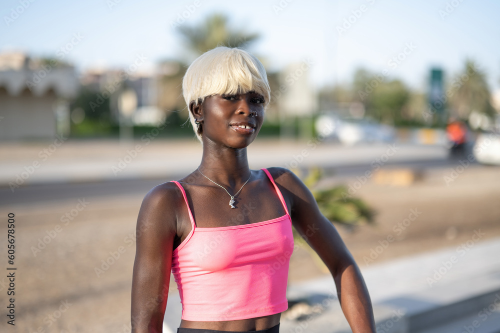Portrait of beautiful African American woman with blond hair in sportswear looking at camera outdoors.