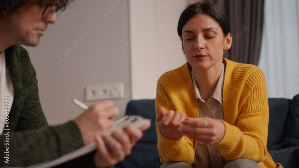 Depressed woman having a therapy session, she is talking and the therapist is writing notes, mental disorders and psychology concept