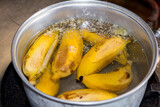 Boiled yellow banana in the hot water with the aluminum pot on the old stove.