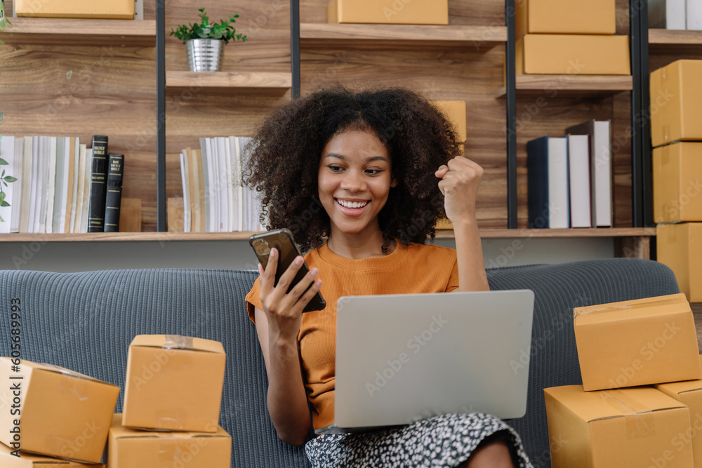 Happy young woman entrepreneur, Smile for sales success after checking order from online shopping store in a smartphone and laptop at home, Concept of merchant business online and eCommerce. Happy young woman entrepreneur, Smile for sales success after checking order from online shopping store in a smartphone and laptop at home, Concept of merchant business online and eCommerce.