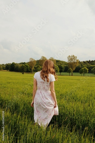 The girl is standing in the field.