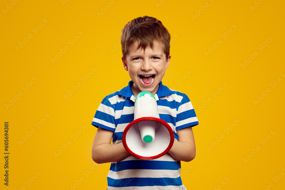 Excited kid leader speaking in megaphone and smiling while standing against yellow background. Young leader concept Excited kid leader speaking in megaphone and smiling while standing against yellow background. Young leader concept