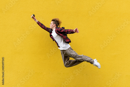 young guy student with backpack and coffee flies forward and rushes to study, energetic man jumps © Богдан Маліцький
