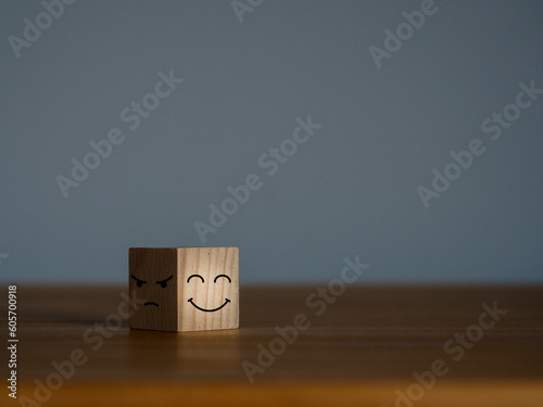 Smiling faces and sad faces in the dark on a wooden cube Emotional state and mental health concept. choosing positive thinking