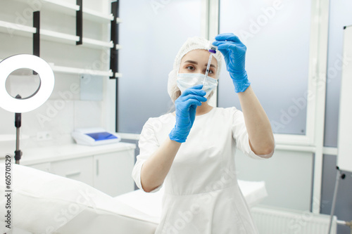 doctor cosmetologist in protective medical mask and gloves holds syringe and jar with injection in cosmetology clinic
