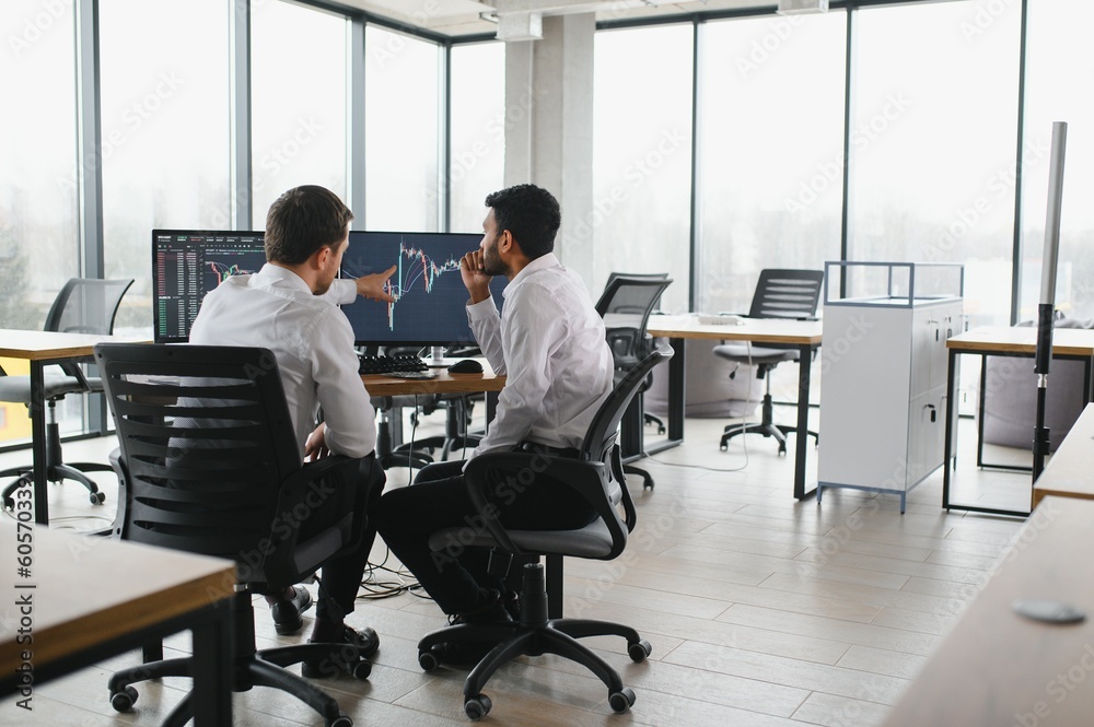 Two successful trader in formalwear pointing at display, analyzing stat and dynamic on forex charts, working in office together