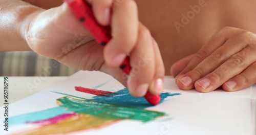 Closeup child hands drawing on paper with crayon