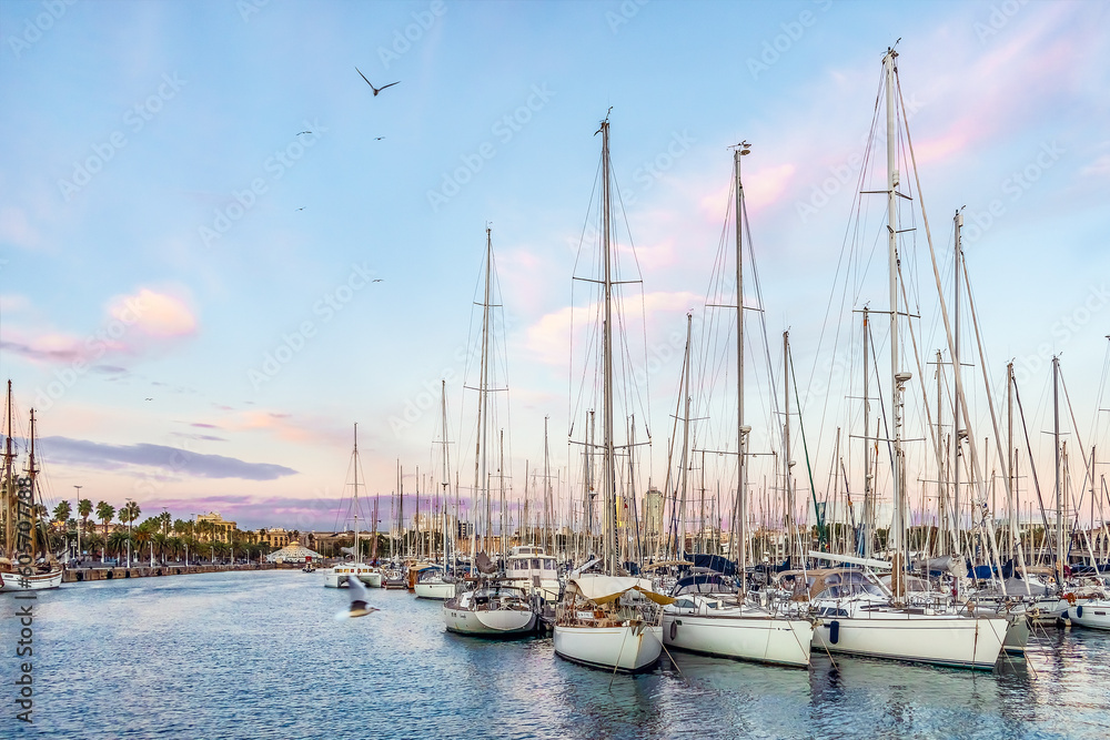 Barcelona, Spain - November 26, 2021: Many yachts are moored in the Port of Barcelona in the evening on the backdrop of a pink-blue sky. Seascape of Mediterranean coastline in Barceloneta at sunset Barcelona, Spain - November 26, 2021: Many yachts are moored in the Port of Barcelona in the evening on the backdrop of a pink-blue sky. Seascape of Mediterranean coastline in Barceloneta at sunset