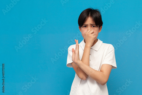 Fotografie asian boy of twelve years covers his nose with his hand and avoids the stink on