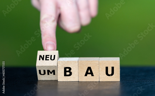 Hand turns wooden cube and changes the German expression 'Umbau' (rebuild) to 'Neubau' (new construction).