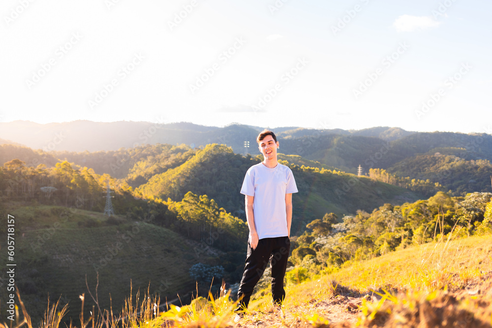 Man standing and smiling after hiking on top of a mountain. Healthy outdoor activities.