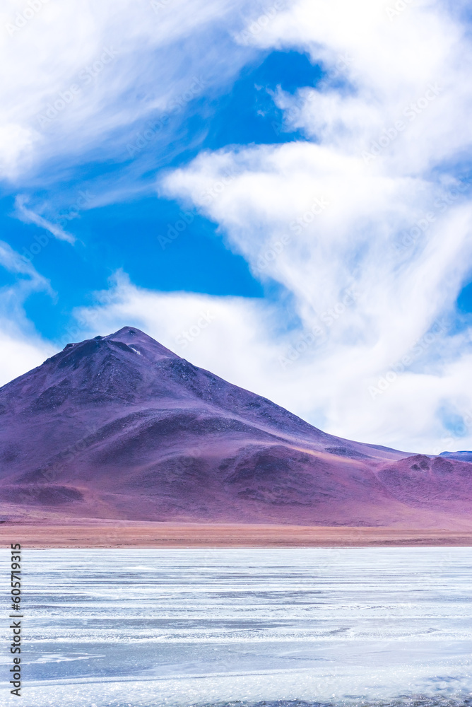 Purple volcano peak next to a frozen lagoon in the bolivian plateau