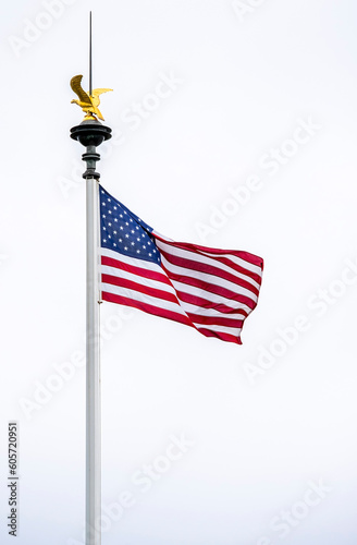 American flag waving on the wind with a golden eagle ontop of the pole