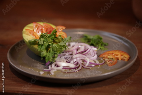 Tropical salad with avocado, tomato, red onion and cilantro. Light food for summer.